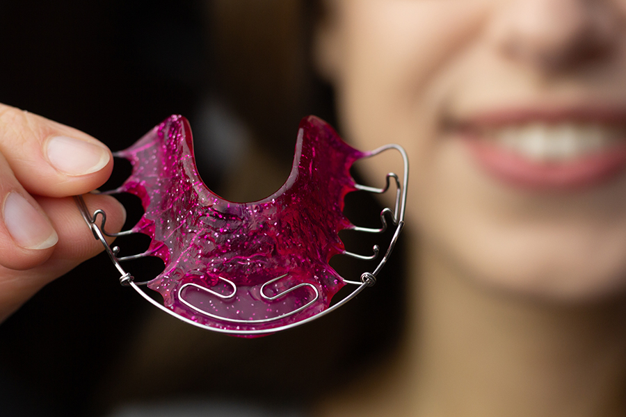 A young woman is putting on her Hawley retainer.