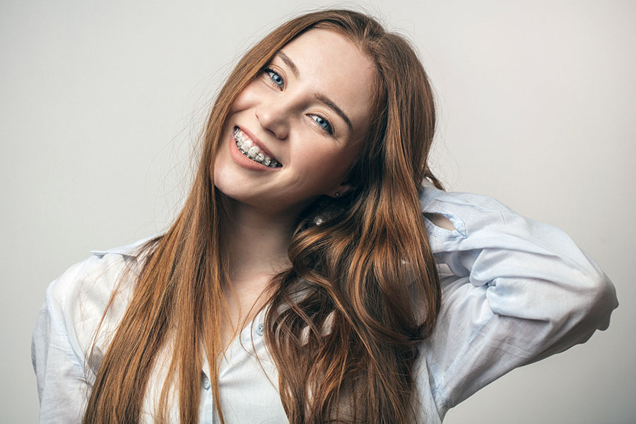 Happy young red-haired woman in braces smiling on white backgrou